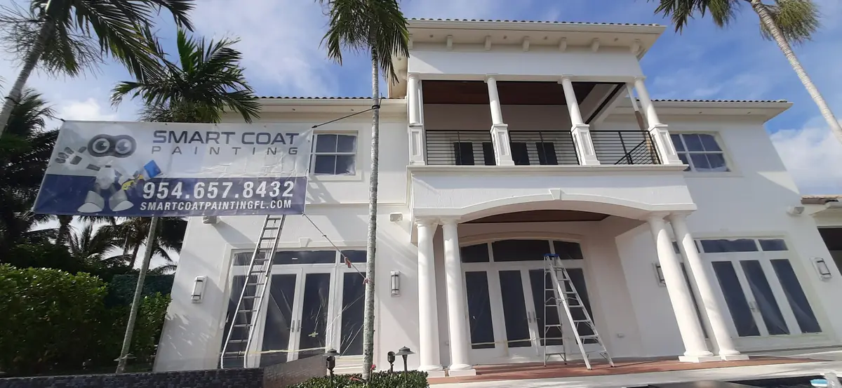 Smart Coat banner and ladders at a two-story white waterfront home