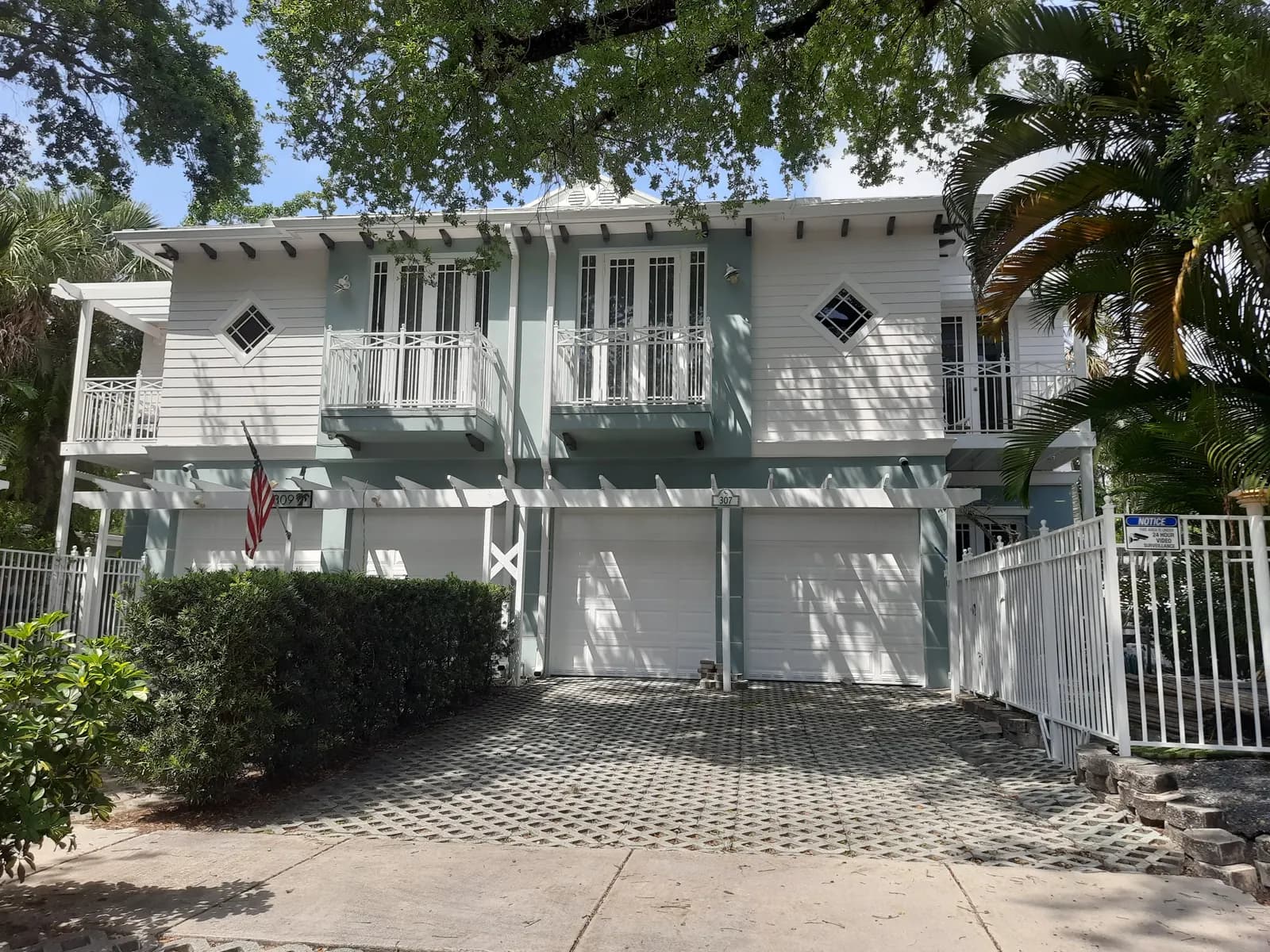 Fort Lauderdale townhomes repainted white with pale blue shutters and garage doors