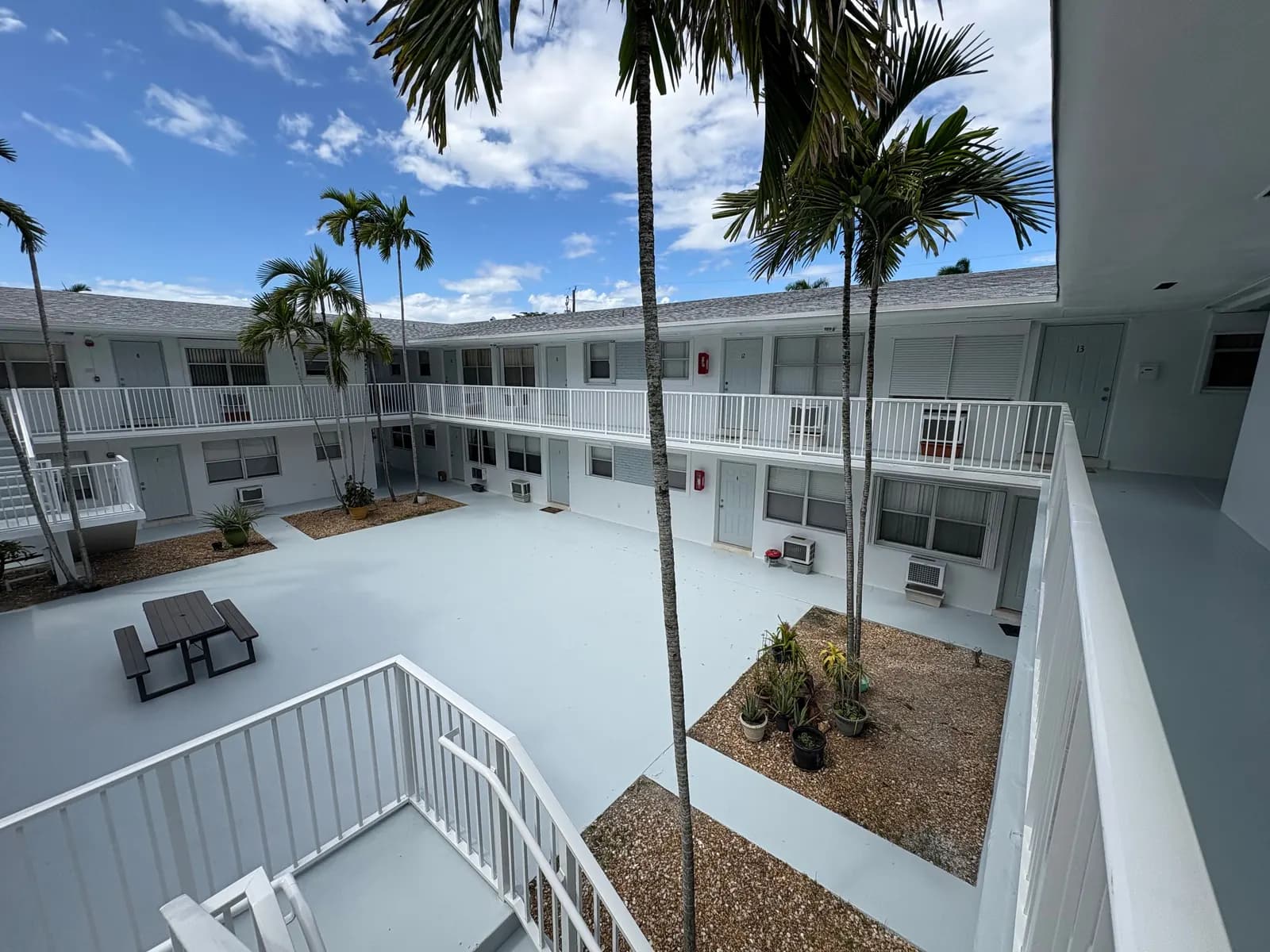 Hollywood courtyard apartments repainted light gray and white around palms