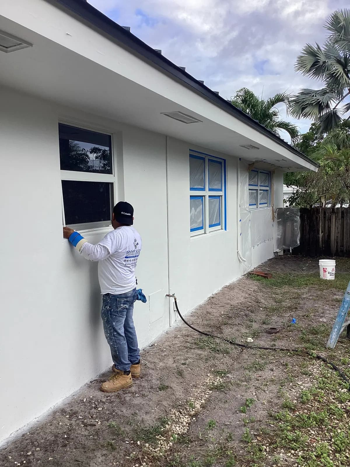 Smart Coat painter masking a window before spraying a stucco wall
