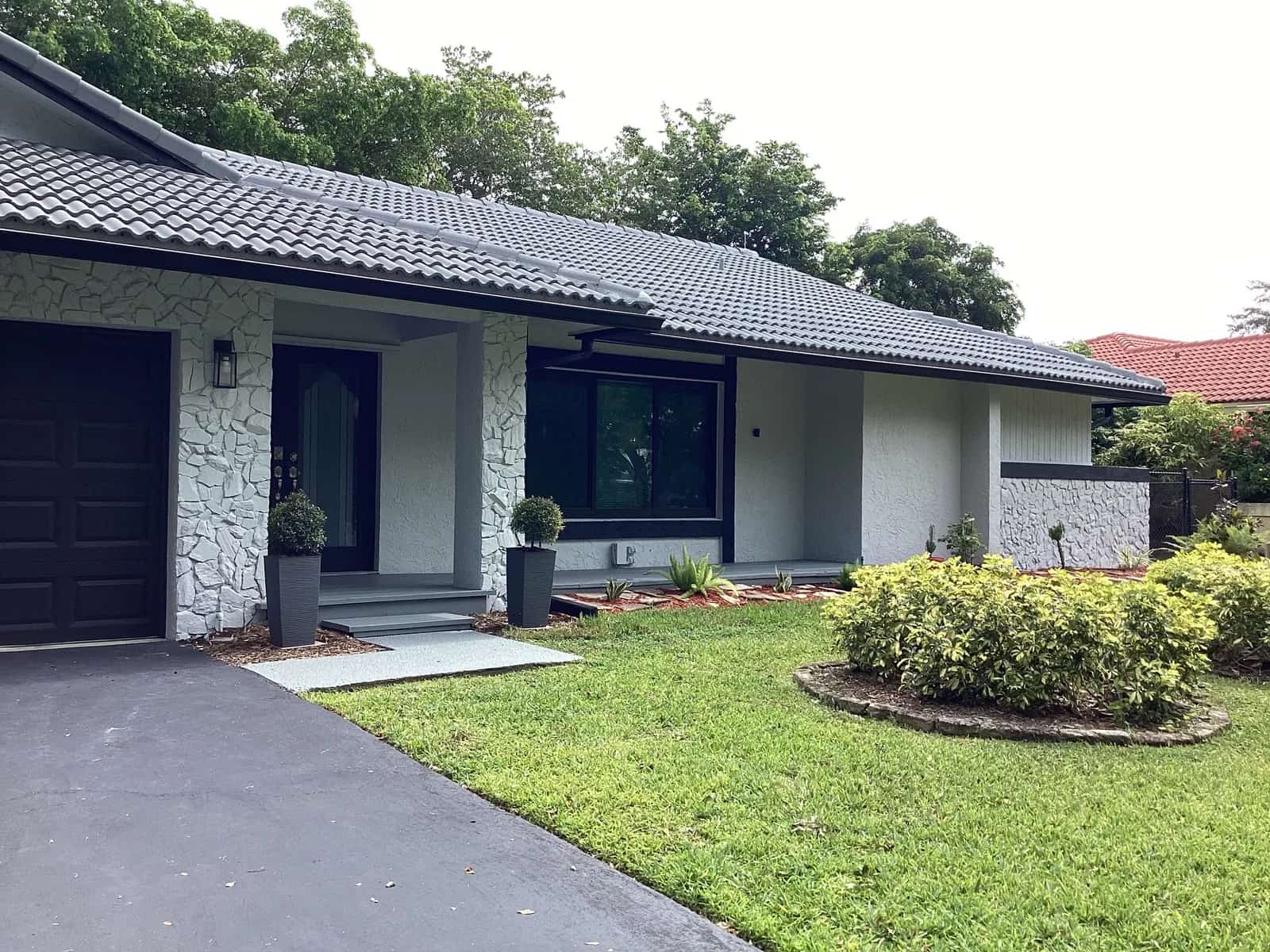 Coral Springs ranch home repainted white with a charcoal tile roof behind a trimmed lawn