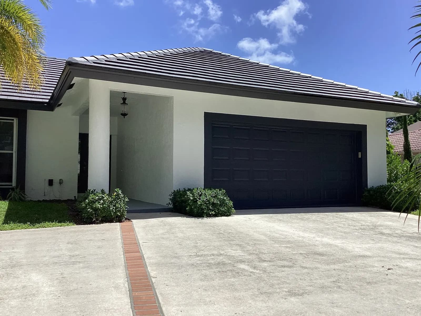 The same West Palm Beach home repainted white with charcoal trim and a black garage door