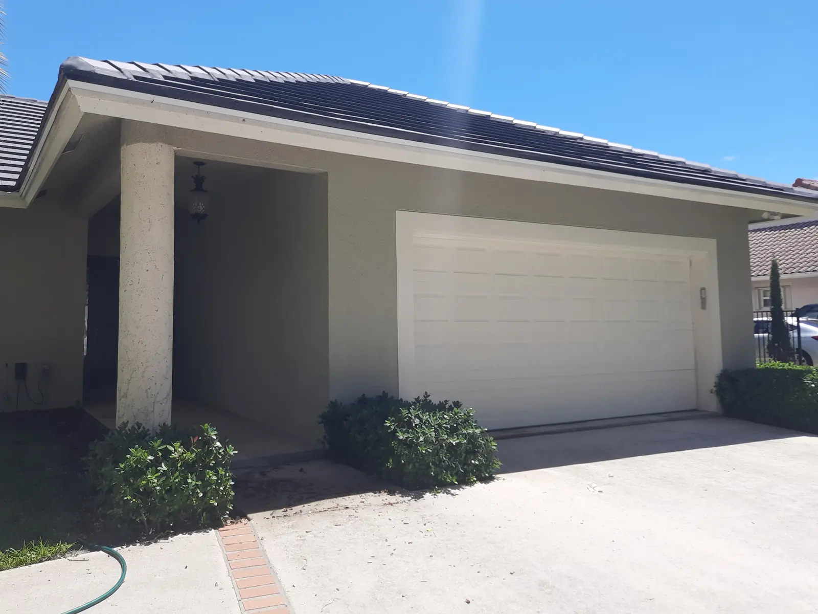 Garage and entry of a West Palm Beach home before repainting: beige stucco and a white garage door