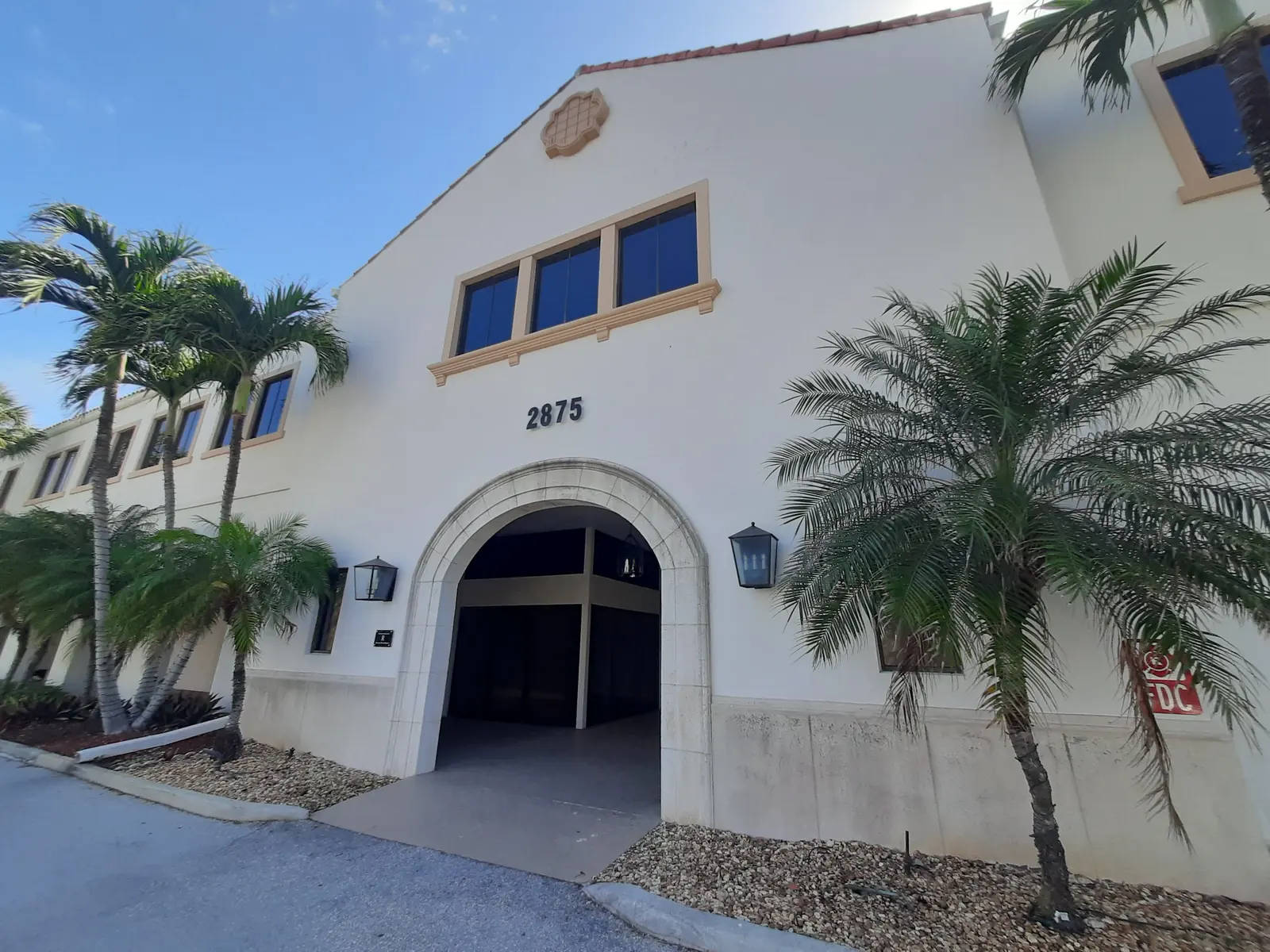 Arched entry of a Palm Beach office building before repainting: cream stucco and tan window trim