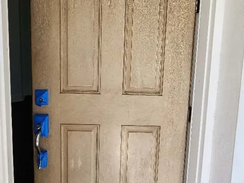 Six-panel front door in Jupiter before staining: a weathered, blotchy tan finish