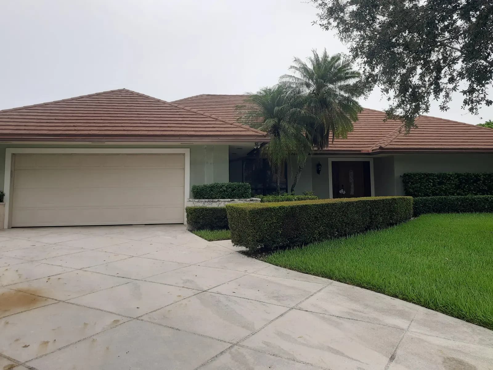Palm Beach Gardens home before repainting: sage green walls and a tan garage door