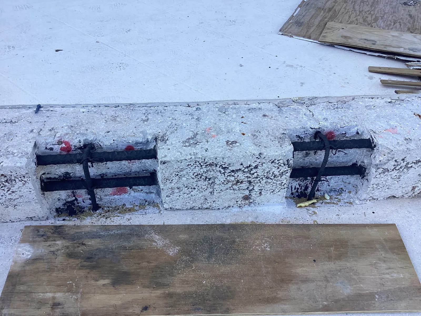 Cut-outs in a concrete deck edge exposing reinforcing steel coated black before patching