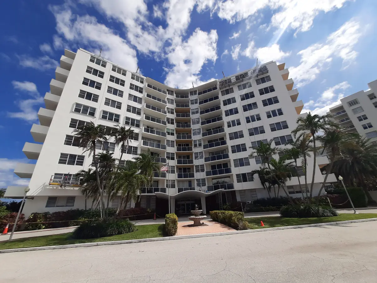 Twelve-story condominium repainted white, palms and a fountain at the entrance
