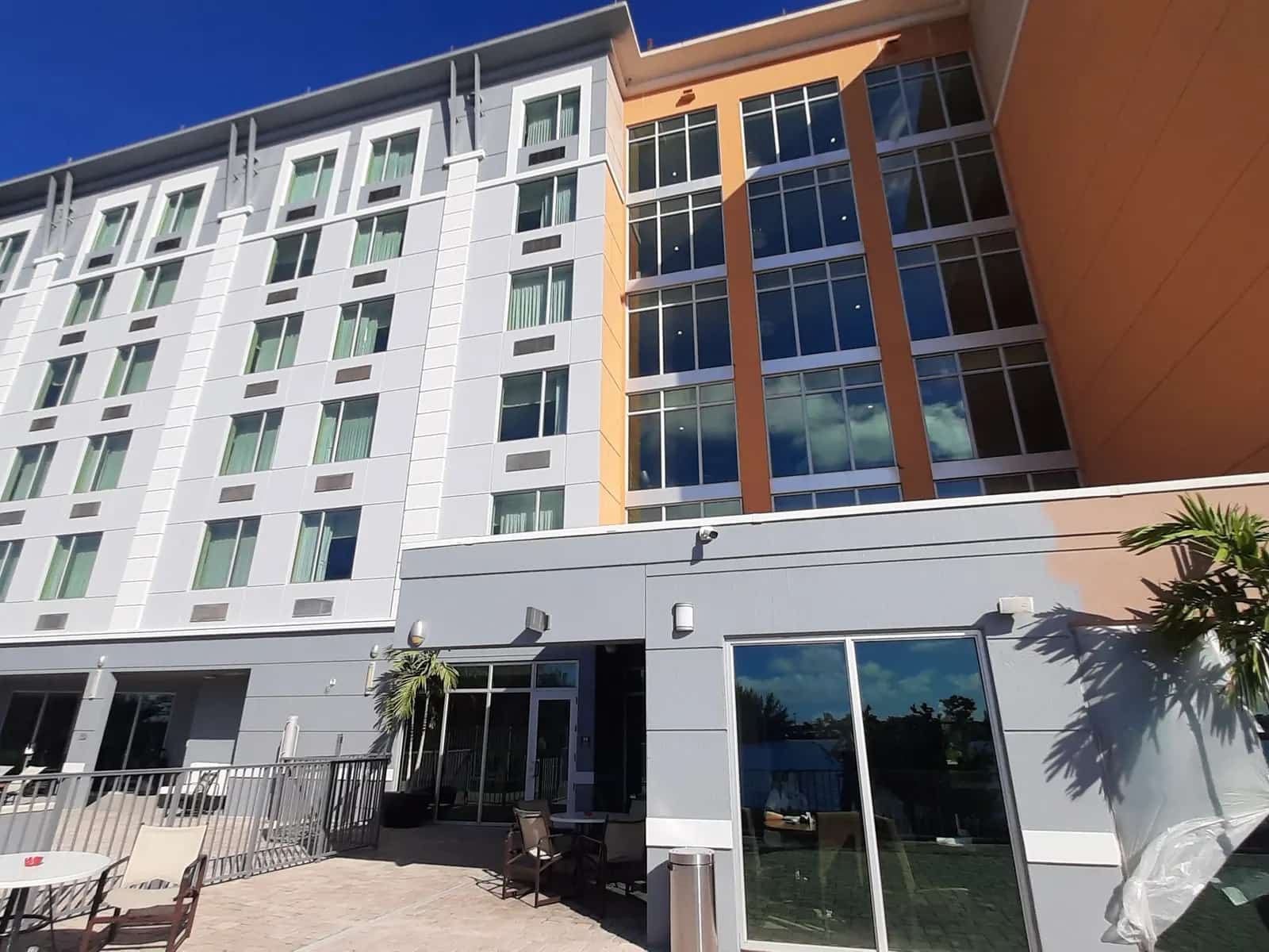 Hotel mid-repaint: one wing finished light gray and white, the other still orange, a swing stage rigged