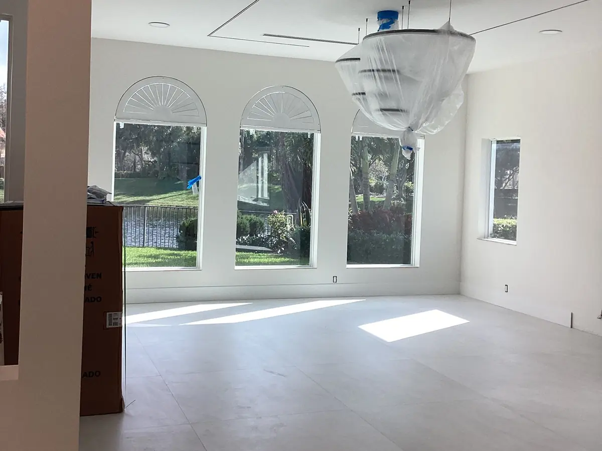 Great room after interior painting: white walls, arched windows and a crystal chandelier