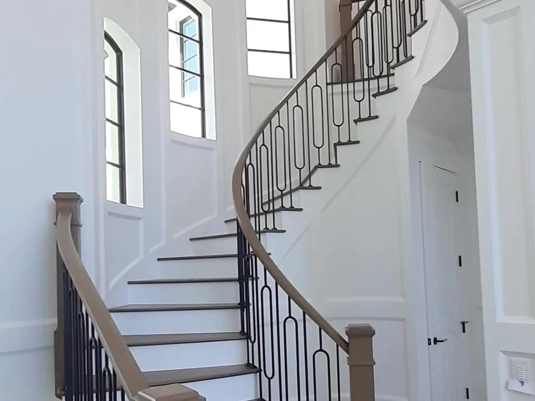 Curved staircase with white risers and iron balusters in a remodeled Jupiter home