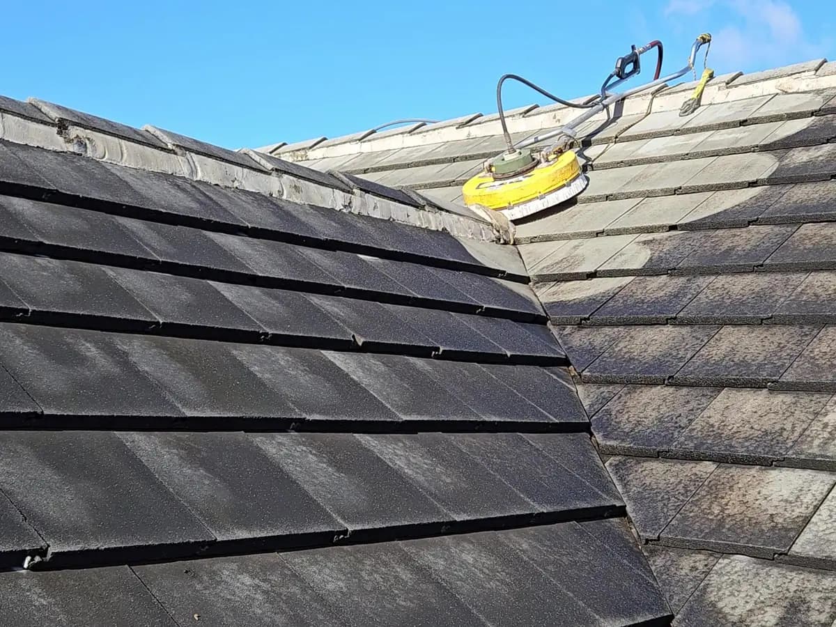 Surface cleaner pressure washing a dark concrete tile roof