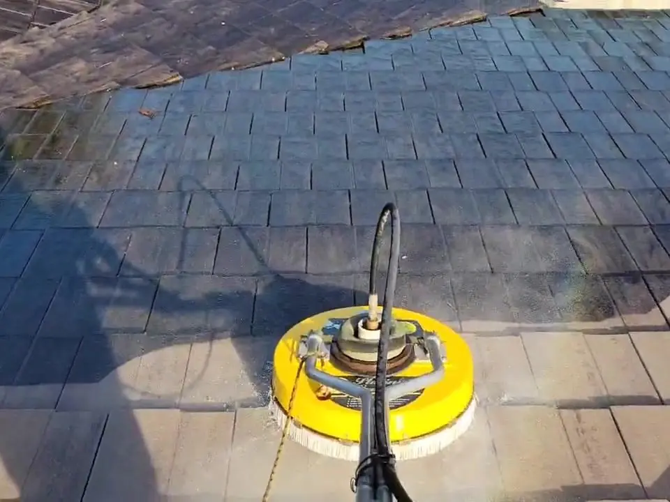 Surface cleaner pressure washing dark tiles, a clean strip showing behind it