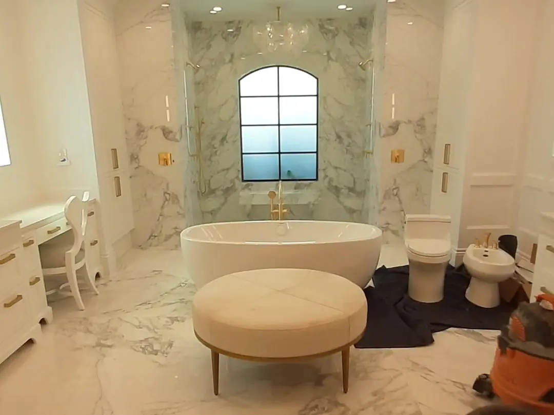 Remodeled primary bathroom in Jupiter: marble floor, a freestanding tub and a chandelier