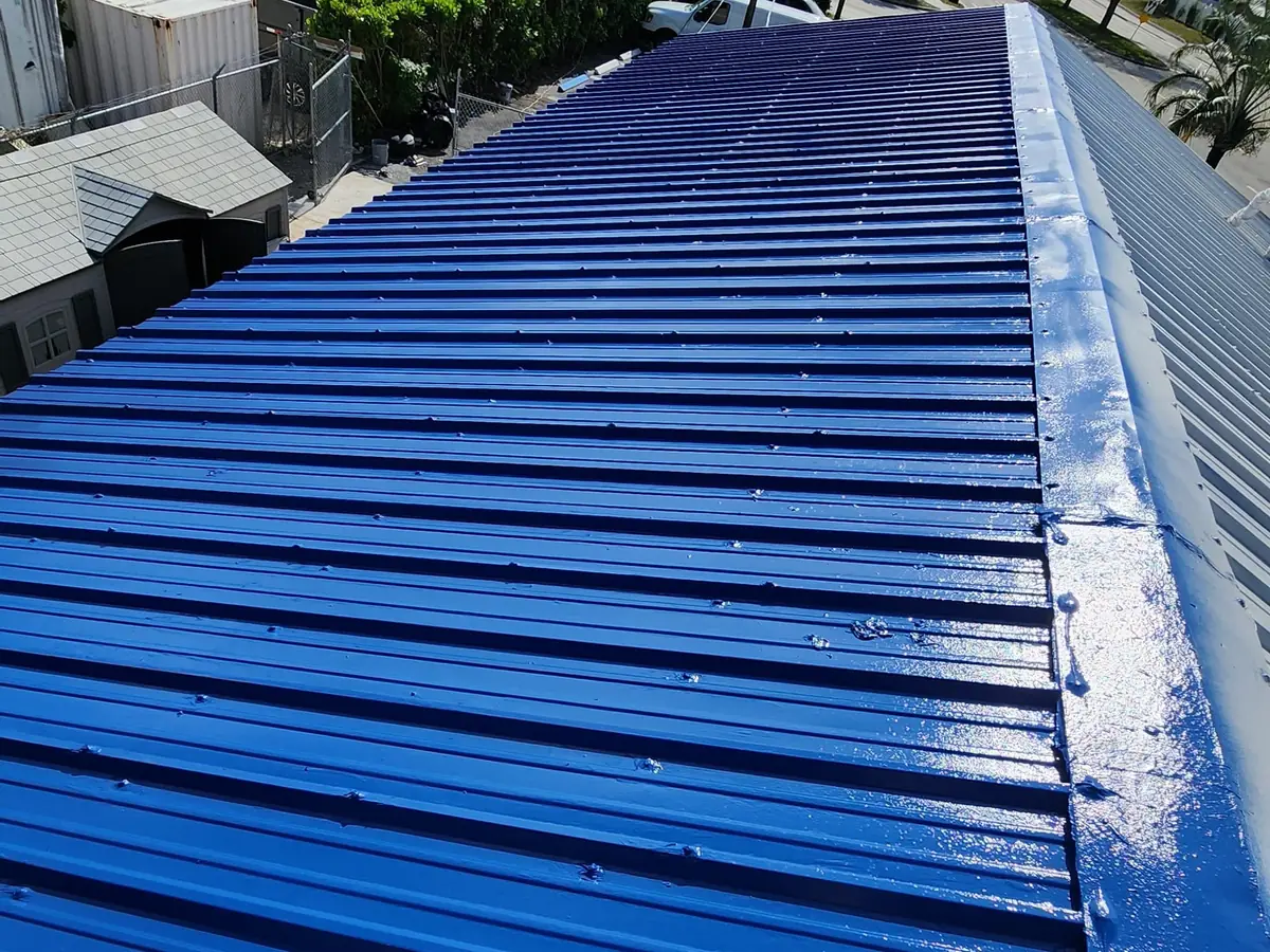 Blue coating being rolled onto a corrugated metal roof