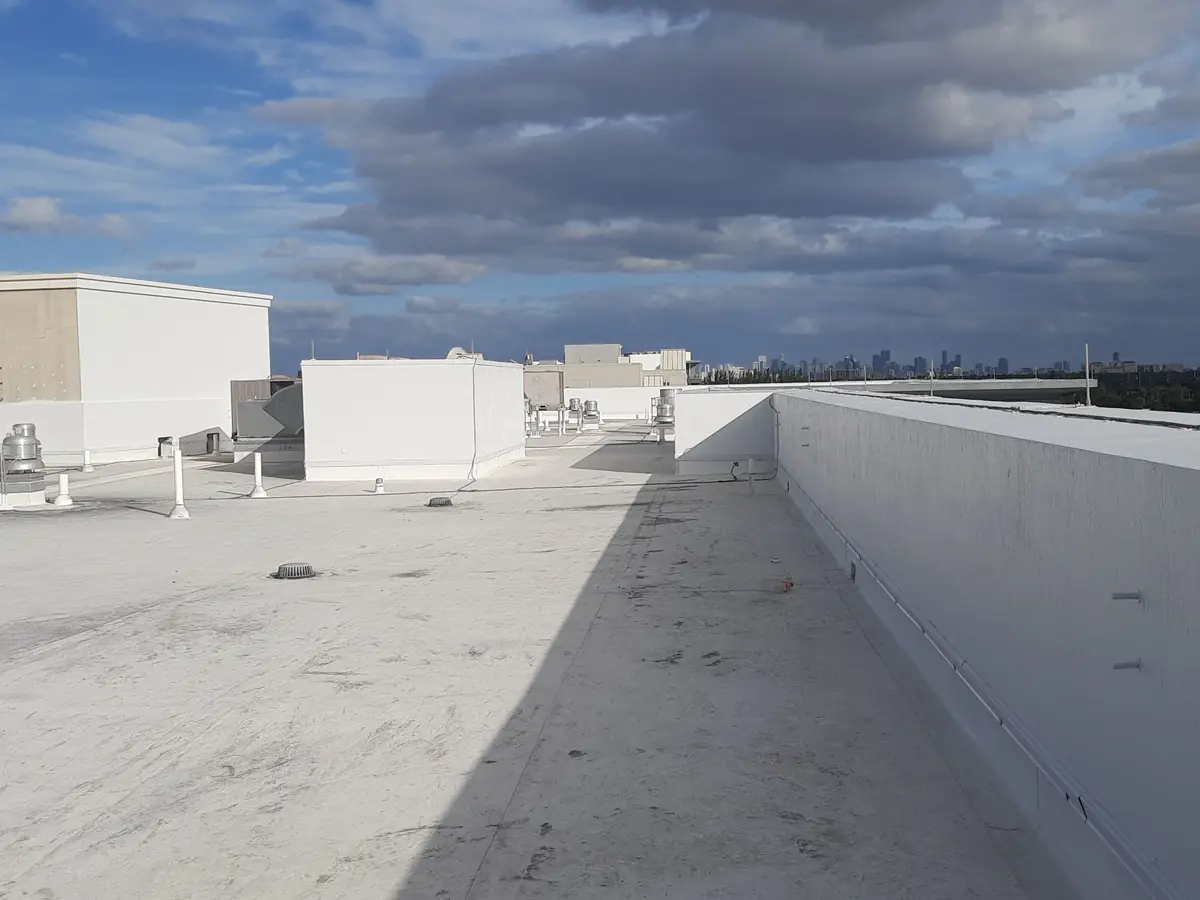 Flat roof finished in a white reflective coating, its parapet walls repainted