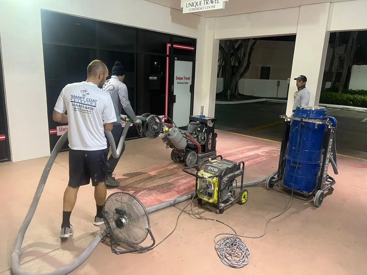 Crew with a diamond grinder, a dust extractor and a generator on a storefront slab