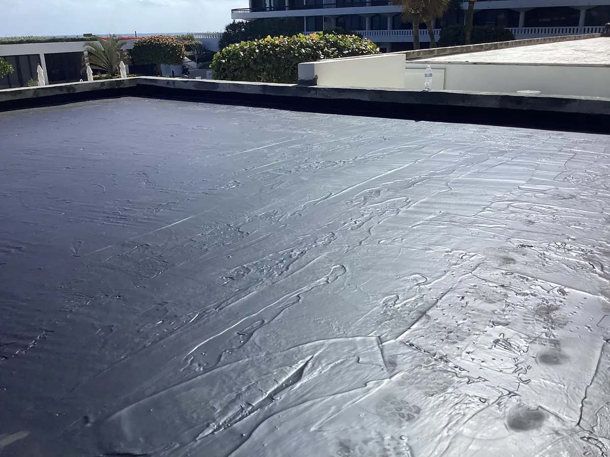 Glossy black waterproofing membrane cured across a flat roof deck